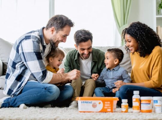 "Family members sitting together in a living room, sharing a warm and supportive moment, with elements suggesting medical challenges subtly present in the background."
