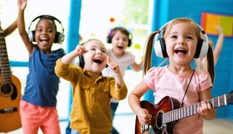 A diverse group of children joyfully engaging with music through dancing, playing instruments, and listening with headphones, representing music's role in enhancing emotional well-being.