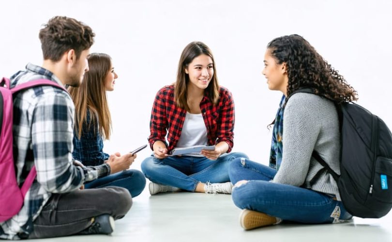 A diverse group of students and a school counselor in a supportive therapy session within a welcoming school environment, representing the importance of accessible mental health services.