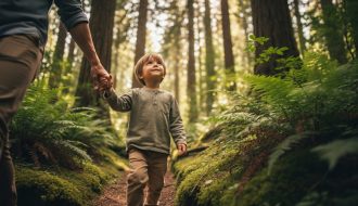 A child walking beside a parent on a mossy forest path, surrounded by tall trees and soft green light filtering through leaves.